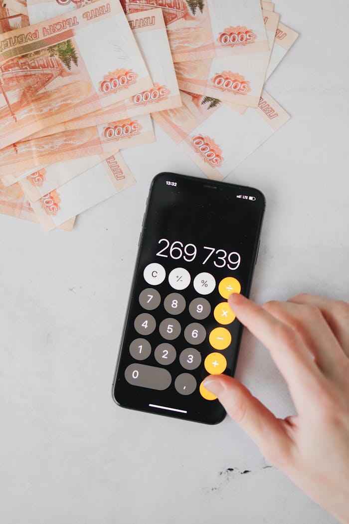 Close-up of smartphone calculator and ruble banknotes, illustrating financial calculations.